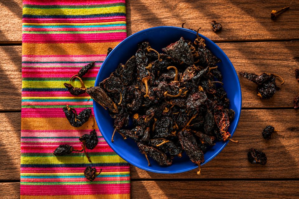 Suszone chilli w niebieskiej misce na pasiastej meksykańskiej tkaninie